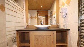 A bathroom with a wooden vanity, a white sink, and a towel rack.