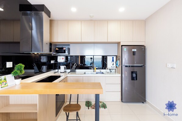 Une cuisine moderne dotée d’appareils électroménagers en acier inoxydable, de meubles en bois et d’un îlot central avec des sièges.