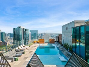 Une piscine sur le toit, dotée d’un plongeoir, d’un espace de détente et offrant une vue sur la ville.