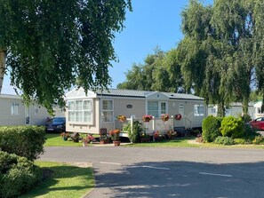 A mobile home with a porch, potted plants, and a car parked in front. - Cleethorpes Pearl Holiday Park by Away Resorts (Cleethorpes)