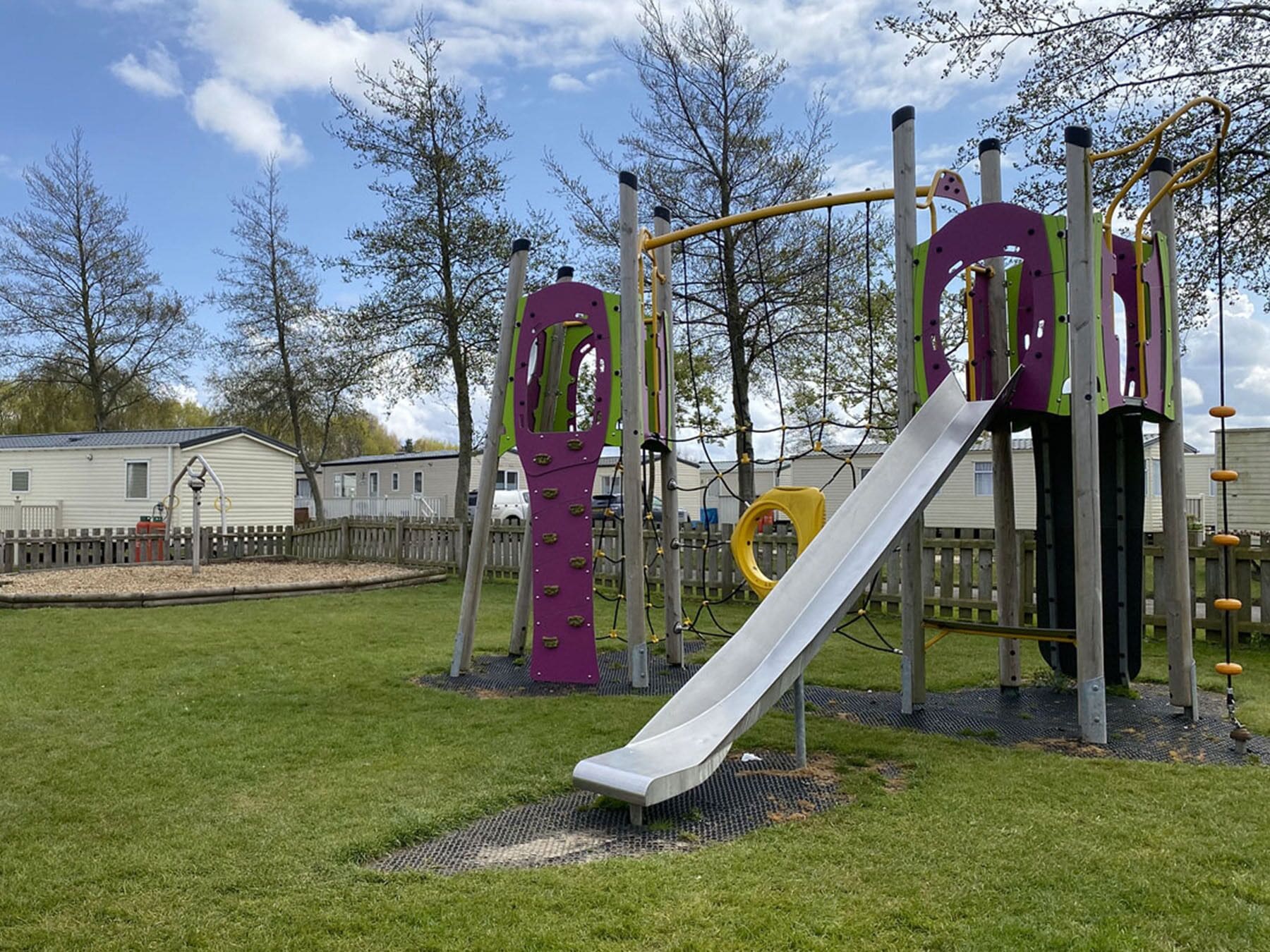 A playground with a slide, climbing structures, and a swing set.
