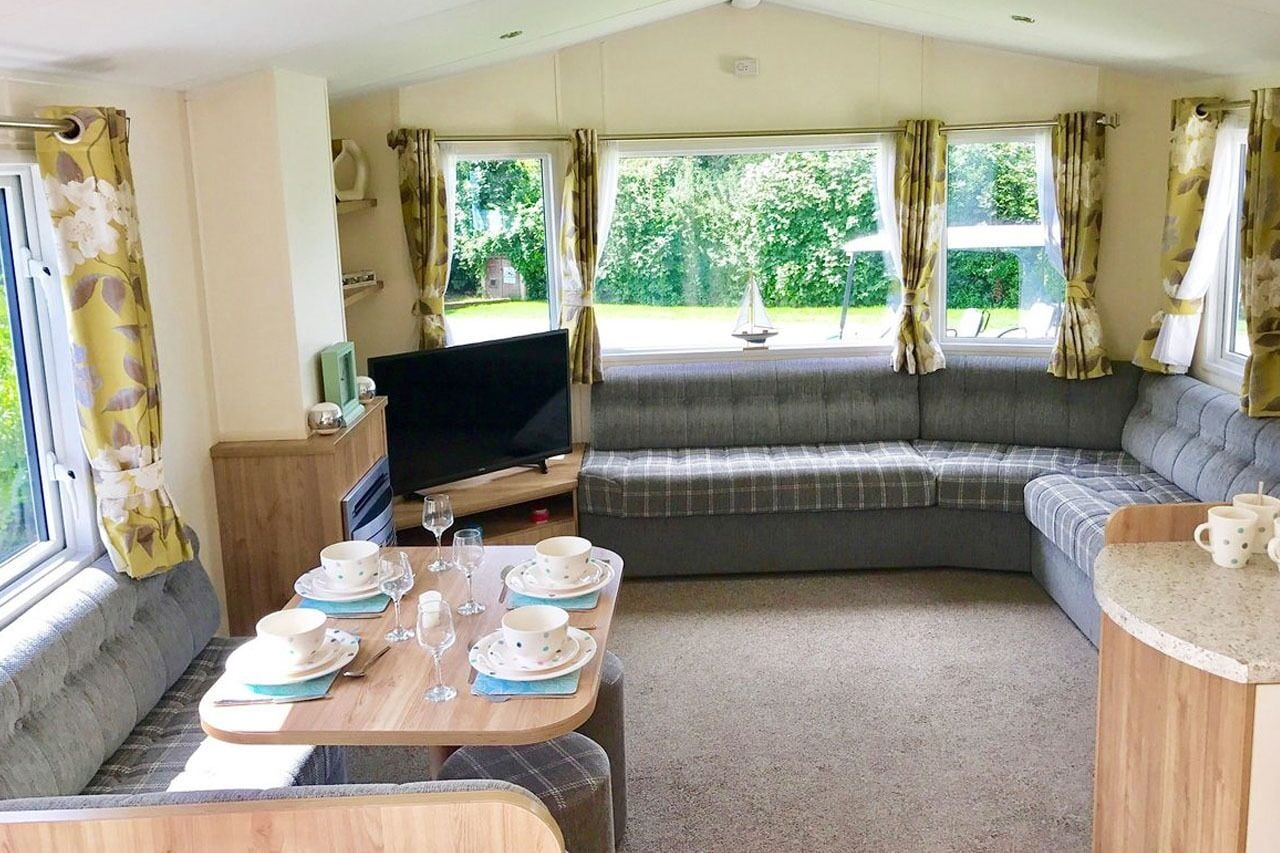 Un intérieur de camping-car confortable, avec un coin repas, un canapé et un téléviseur.