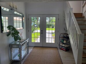 Enter a welcoming space with a large mirror, a potted plant, and a view of the lawn through the double glass door.