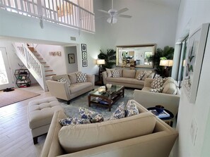 Relax in this stylish living room with a high ceiling, staircase, and comfortable seating area.