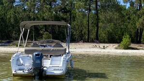Un bateau-ponton baptisé GIULIA était amarré sur une plage de sable, avec des arbres en arrière-plan.