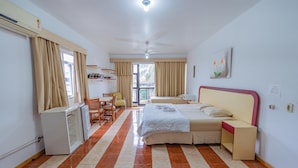 Une chambre d’hôtel avec un lit, un bureau, une chaise, une armoire et une fenêtre avec des rideaux.