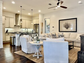 Una cocina moderna con muebles blancos, electrodomésticos de acero inoxidable e iluminación colgante.