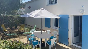 A patio with a table and chairs, a white umbrella, and a blue door. - Superb Vacation House With Garden And Terrace (La Tranche-sur-Mer)