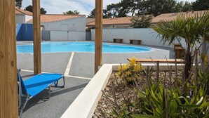 A swimming pool area with a blue lounge chair, wooden pergola, and a small garden with plants and pebbles. - Superb Vacation House With Garden And Terrace (La Tranche-sur-Mer)