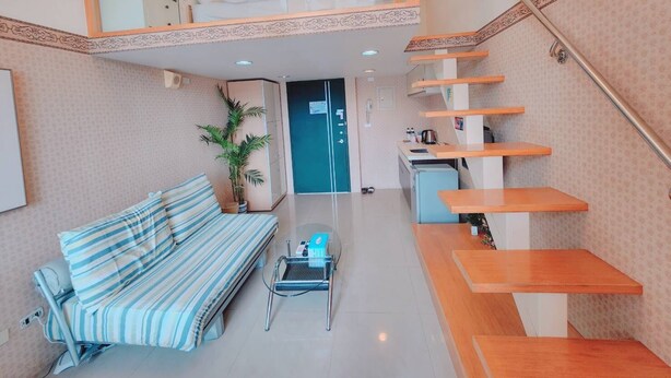 A modern living room with a sofa, a coffee table, and a staircase leading to an upper level. - 樓中樓溫泉大浴缸(也有平面房型)，免費停車，10秒到礁溪湯圍溝溫泉公園 (Jiaoxi)