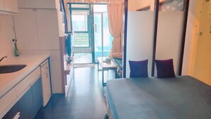 A compact hotel room with a kitchenette, a bed, a small table, and a view of the outdoors. - 樓中樓溫泉大浴缸(也有平面房型)，免費停車，10秒到礁溪湯圍溝溫泉公園 (Jiaoxi)