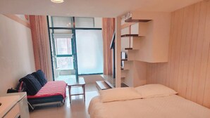 A modern hotel room with a large bed, a desk, a chair, and a small table. There is a window with curtains and a view of buildings outside. - 樓中樓溫泉大浴缸(也有平面房型)，免費停車，10秒到礁溪湯圍溝溫泉公園 (Jiaoxi)