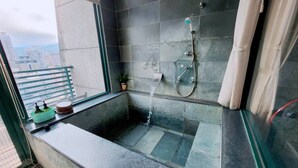 A small bathroom with a bathtub, a shower, and a window. - 樓中樓溫泉大浴缸(也有平面房型)，免費停車，10秒到礁溪湯圍溝溫泉公園 (Jiaoxi)