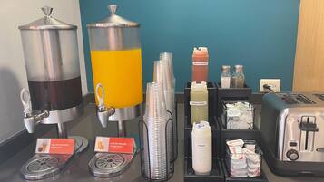 Una barra de zumos con dispensadores, botellas de condimentos y un tostador.