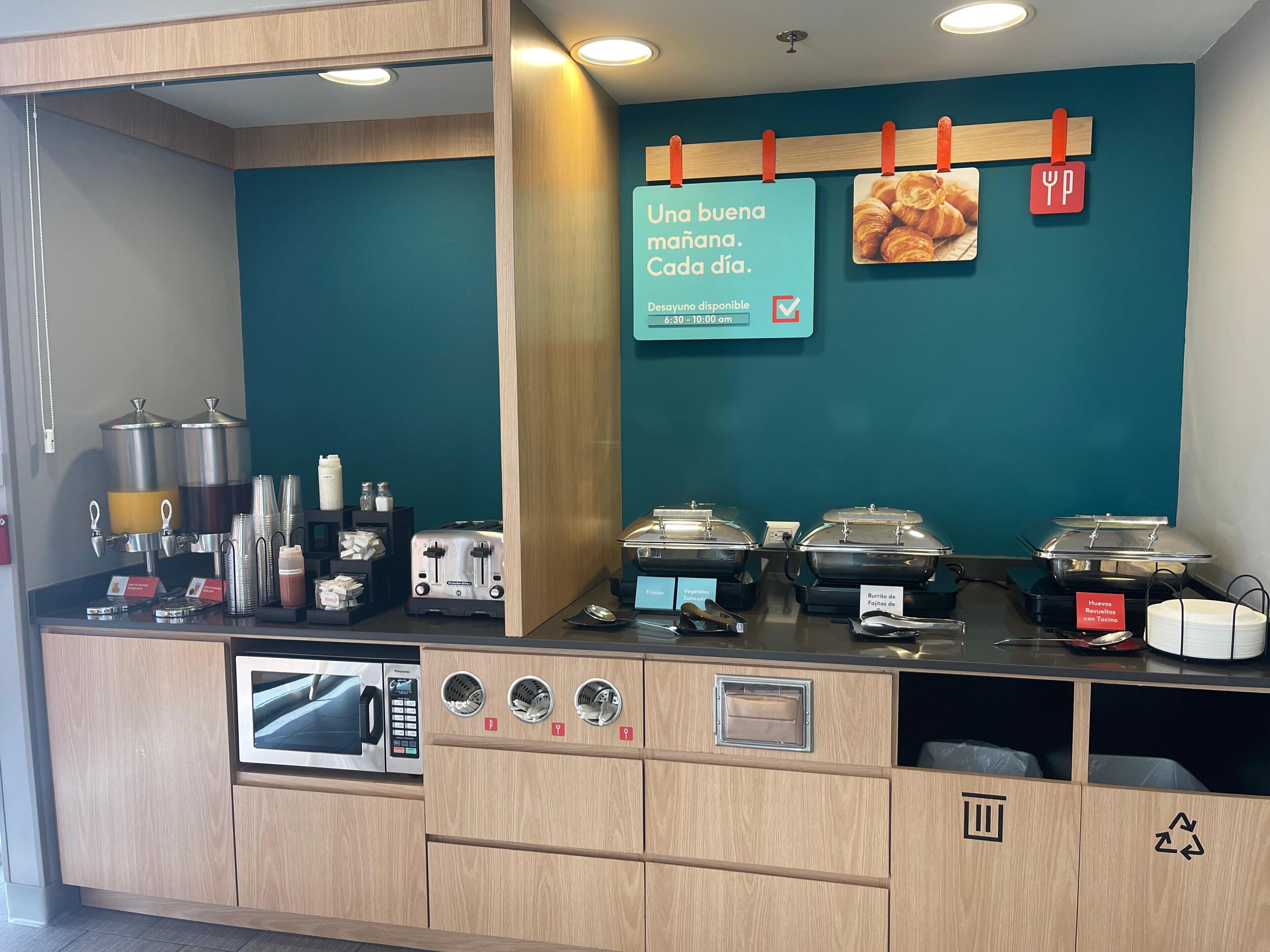 A breakfast station with a coffee machine, toaster, and various food containers.