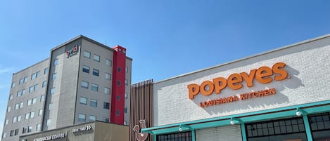 A building with a Starbucks Coffee sign, a Popeyes Louisiana Kitchen, and a tall building with an 'avid' sign.