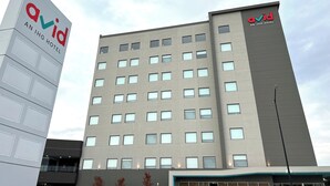 Un edificio moderno de hotel con un letrero destacado que dice 'Qovid An IHG Hotel'.