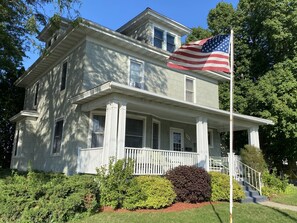Uma casa de dois andares com varanda e um mastro com a bandeira americana.