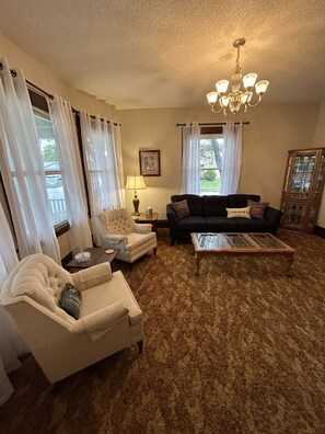 A living room with a chandelier, a sofa, a chair, and a coffee table. - Large Home 5 min to Field of Dreams (Dyersville)