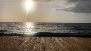 A wooden deck overlooking the ocean with the sun shining through the clouds. - Welcome to Domaine U Pozzu (SISCO)