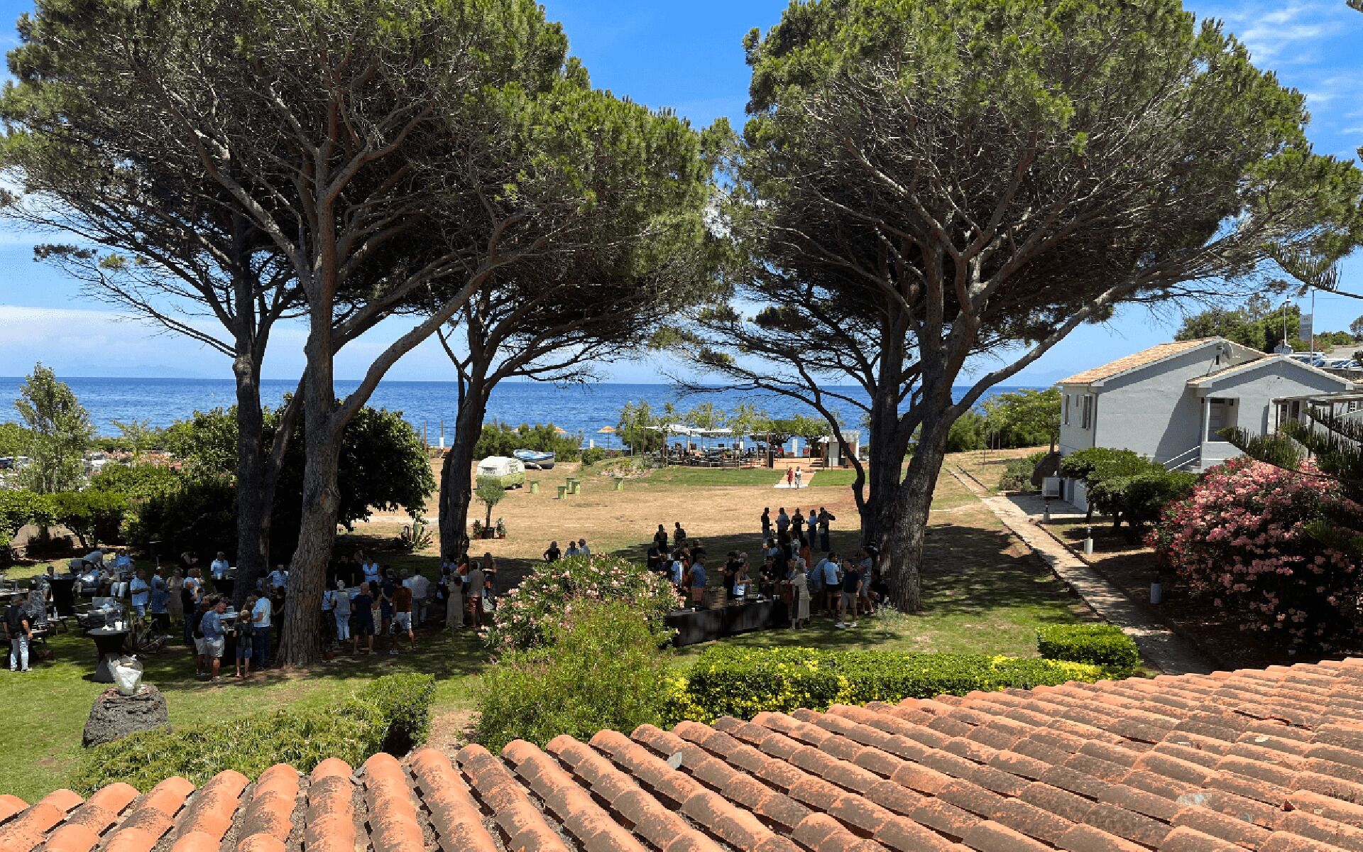 A coastal property with a patio area, a view of the sea, and a building with a tiled roof.