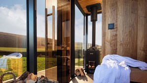 A modern interior with a fireplace, a glass door leading outside, and a wicker basket of firewood.