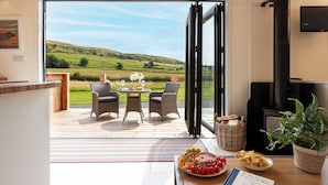 A modern interior with a large sliding glass door leading to a deck with a scenic view.