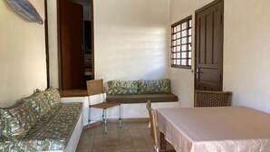 A small, enclosed room with a sofa, a bench, a table, and wicker chairs.
