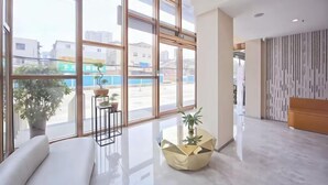 Eine moderne Hotellobby mit großen Fenstern, einer Sitzecke und einer Rezeption.