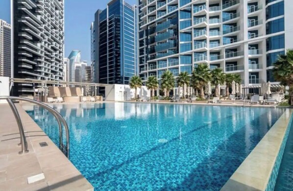 Relax by the infinity pool surrounded by palm trees and lounge chairs.