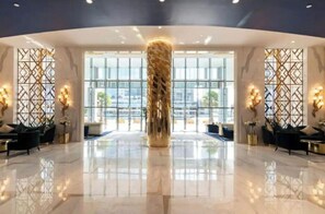 Experience the grandeur of our lobby, featuring a high ceiling, polished floors, and comfortable seating areas with sofas and side tables.