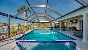 Piscina techada con vista de los alrededores, incluyendo una casa y palmeras.