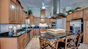 Una cocina amplia con armarios de madera, una isla grande y un ventilador de techo.