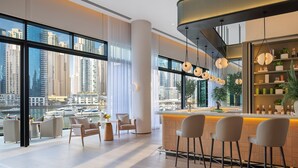 Un moderno vestíbulo de hotel con amplios ventanales, una zona de bar y asientos.