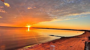 A beach scene with a sunset, calm water, and a wooden fence.