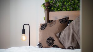 A bed with a white textured bedspread, a wooden headboard, and a wall-mounted light fixture. - Maritime Quarter  - 2 Bedroom Apartment - SA1 Beach Front (Fisherman's Way) (Swansea)