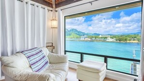 A room with a large window offering a view of a body of water and distant buildings.