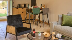 A modern living room with a dining area, a kitchen, and a large window. - Suite Terrasse 2 at Domaine de la Commanderie de Ballan (Ballan-Miré)