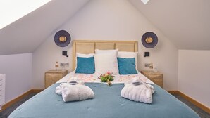 A bedroom with a sloped ceiling, a wooden headboard, two bedside tables, and a skylight. - Suite Terrasse 2 at Domaine de la Commanderie de Ballan (Ballan-Miré)