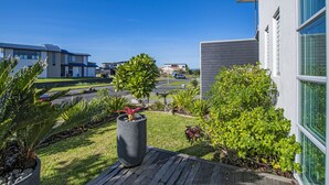Un quartier résidentiel moderne doté d’un jardin bien entretenu, d’une terrasse en bois et offrant une vue dégagée sur la rue et les maisons voisines.