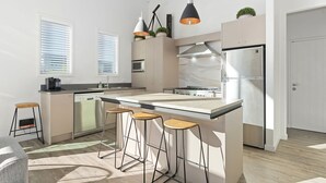 Une cuisine moderne dotée d’un îlot central, de tabourets de bar, d’un four à micro-ondes, d’une cuisinière et d’un réfrigérateur.