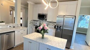 Una cocina moderna con gabinetes blancos, electrodomésticos de acero inoxidable y encimera de mármol.