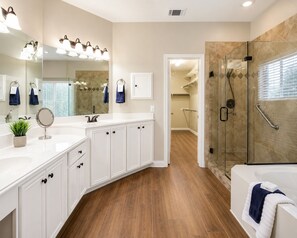 A modern bathroom with a glass shower enclosure, a white vanity with a mirror, and a walk-in shower.