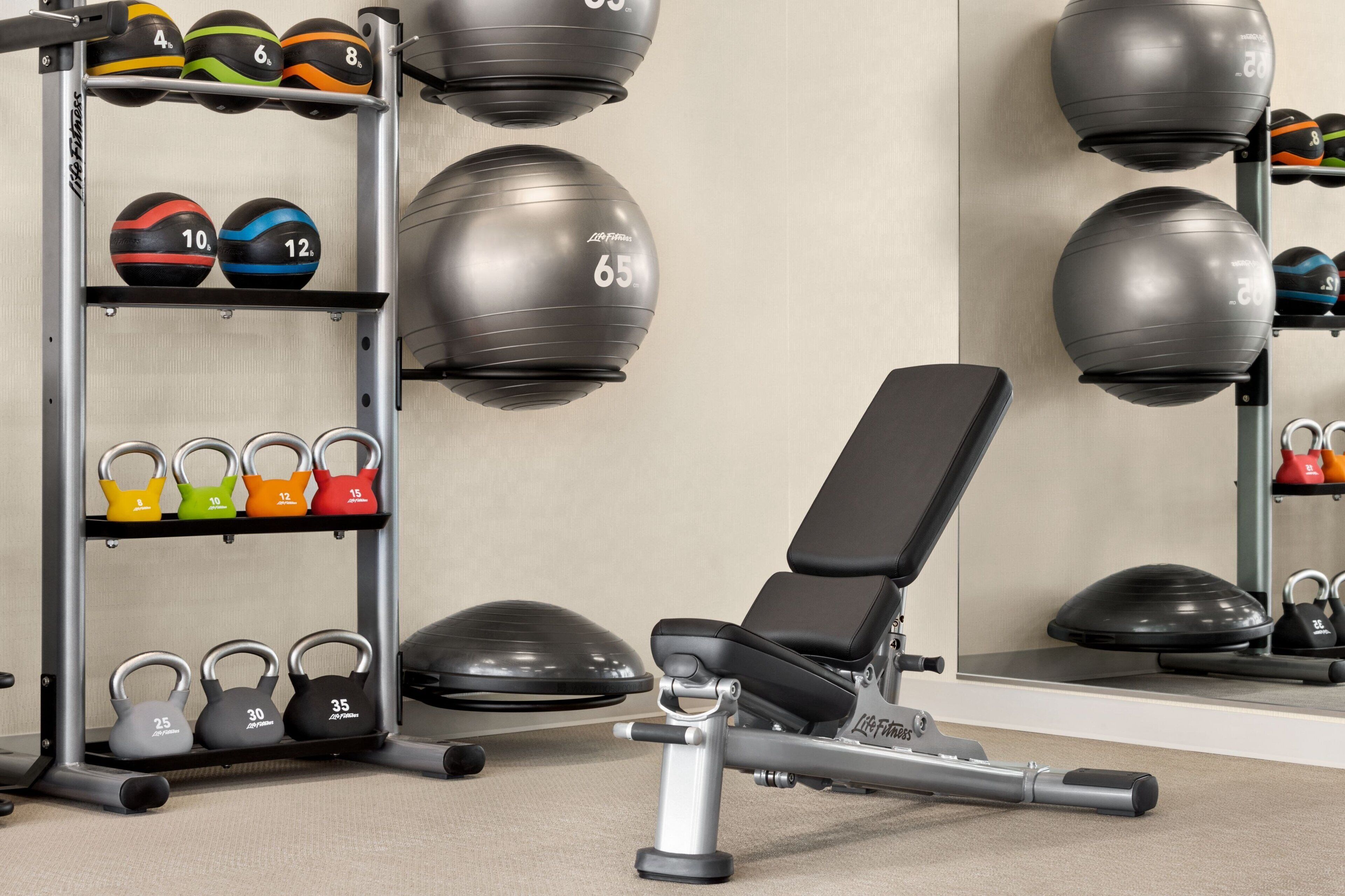 Een sportschool met trainingsapparatuur, waaronder kettlebells en medicine balls.