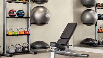 Een sportschool met trainingsapparatuur, waaronder kettlebells en medicine balls.