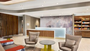 A modern lobby with a reception desk, seating area, and a display of snacks.