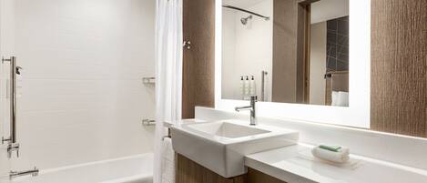 A modern bathroom with a bathtub, a shower, and a vanity with a large mirror.