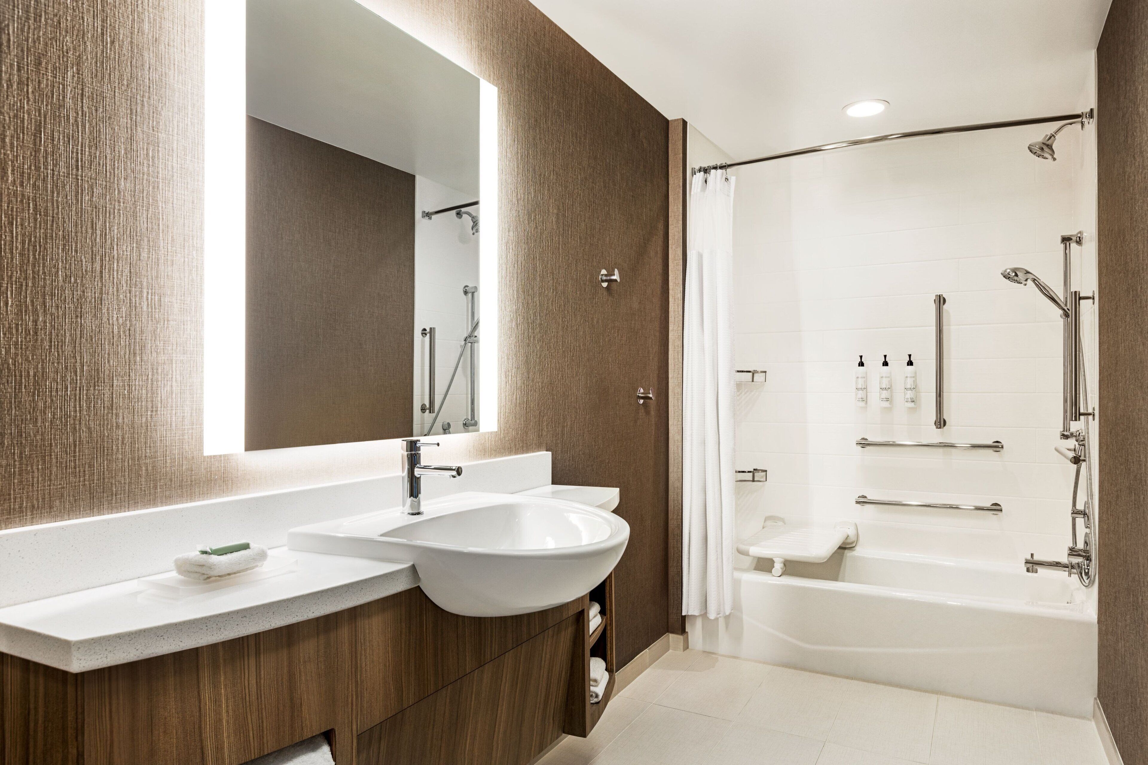 A modern bathroom with a large mirror, two sinks, a bathtub, and a shower.