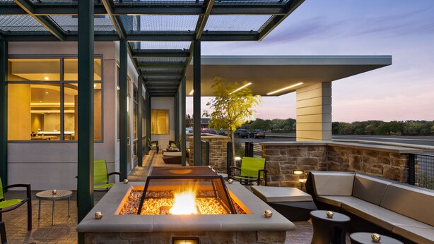 An outdoor patio area with a stone fire feature, seating, and a view of the surrounding landscape.