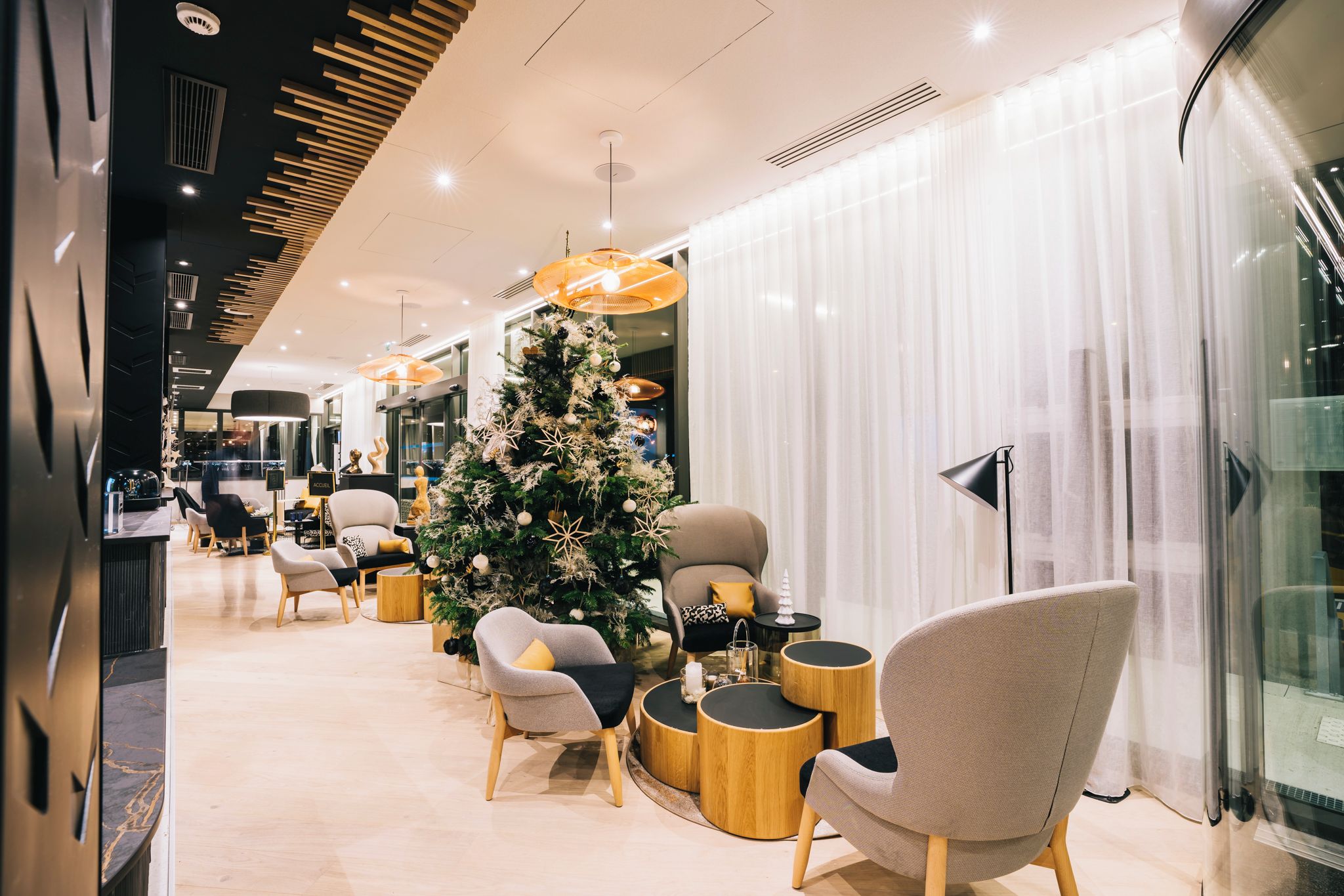 A modern interior with a Christmas tree, seating area, and a glass partition.